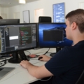 Ein Programmierer arbeitet an einem Computer, indem er Code auf zwei Monitoren schreibt und überprüft.