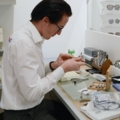 Ein Augenoptiker arbeitet in einem Optikerladen und passt eine Brille an.