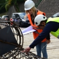 Zwei bautechnische BauarbeiterInnen mit Helmen und Sicherheitswesten begutachten auf einer Baustelle eine Stahlkonstruktion.