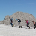 Das Bild zeigt eine Gruppe von Bergsteigern, die in einer schneebedeckten Berglandschaft wandern.