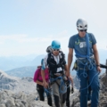 Auf dem Bild sind Bergsteiger zu sehen, die in einer Seilschaft auf einem felsigen Berg unterwegs sind.
