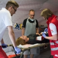SanitäterInnen versorgen eine Person auf einer Trage in einem medizinischen Notfallzelt.