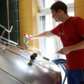 Ein Brautechniker arbeitet an einer Brauerei-Anlage und bedient ein Steuerungselement.