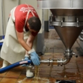 Ein Brau- und Getränketechniker arbeitet in einer Brauerei und reinigt eine Leitung.