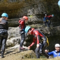 Auf dem Bild sind Personen in Neoprenanzügen und Helmen zu sehen, die an einer geführten Outdoor-Aktivität wie Canyoning teilnehmen.