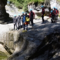 Das Bild zeigt eine Gruppe von Menschen beim Canyoning, begleitet von einem Guide, der sie durch eine felsige Schlucht führt.