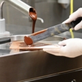 Auf dem Bild ist zu sehen, wie ein Chocolatiers Schokolade temperiert.