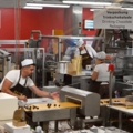 Das Bild zeigt MitarbeiterInnen der Schokoladenmanufaktur, die Trinkschokolade verpacken.