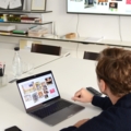 Ein Creative Director arbeitet am Laptop in einem Büro und betrachtet Präsentationen auf einem Bildschirm.