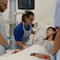Auf dem Bild betreuen diplomierte Gesundheits- und KrankenpflegerInnen eine Patientin in einem Krankenhauszimmer und überwachen ihre Vitalfunktionen.