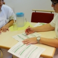 Zwei diplomierte Gesundheits- und Krankenpflegerinnen in Berufskleidung besprechen und bearbeiten Dokumente.