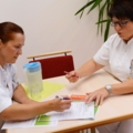 Zwei diplomierte Gesundheits- und Krankenpflegerinnen in weißer Berufskleidung bearbeiten Dokumente.