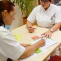 Zwei diplomierte Gesundheits- und Krankenpflegerinnen in Arbeitskleidung besprechen Dokumente.