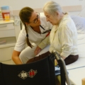 Eine Pflegeassistentin betreut eine ältere Person in einem Krankenhaus.