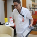 Eine Pflegeassistentin trägt medizinische Ausrüstung und Dokumente.
