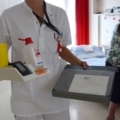 Auf dem Bild ist eine Pflegeassistentin zu sehen, die medizinische Utensilien und Dokumente trägt.