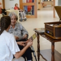 Auf dem Bild ist eine Pflegeassistentin zu sehen, die sich um eine ältere Person in einem Pflegeheim kümmert.