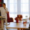 Eine Pflegeassistentin hält eine Präsentation für Senioren in einem Gemeinschaftsraum.