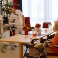 Eine Pflegeassistentin hält eine Präsentation für Senioren in einem Gemeinschaftsraum.