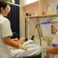 Das Bild zeigt diplomierte Gesundheits- und Krankenpflegerinnen, die sich um einen Patienten im Krankenhaus kümmern.