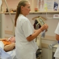 Auf dem Bild sind diplomierte Gesundheits- und Krankenpflegerinnen in einem Krankenhauszimmer zu sehen, die sich um einen Patienten kümmern.