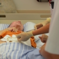 Das Bild zeigt diplomierte Gesundheits- und Krankenpflegerinnen, die eine medizinische Behandlung an einem Patienten durchführen.