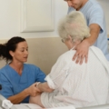 Auf dem Bild sind diplomierte Gesundheits- und KrankenpflegerInnen zu sehen, das einer älteren Person im Krankenhaus helfen.