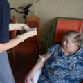 Eine diplomierte Gesundheits- und Krankenpflegerin führt eine medizinische Versorgung bei einer älteren Person durch.