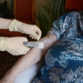 Eine diplomierte Gesundheits- und Krankenpflegerin führt bei einer älteren Person eine Blutabnahme durch.
