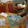 Auf dem Bild bereitet eine diplomierte Gesundheits- und Krankenpflegerin mit Handschuhen medizinische Materialien auf einem Tisch vor.