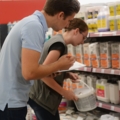 Zwei BaumarktverkäuferInnen führen in einem Geschäft Inventur durch, indem sie Regale mit Produkten überprüfen und Notizen machen.