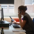 Auf dem Bild ist eine Baumarktverkäuferin zu sehen, die an einem Computer arbeitet und dabei telefoniert.