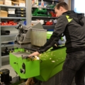Ein Sportartikelverkäufer bedient eine Maschine in einer Werkstattumgebung, um einen Ski zu schleifen.