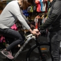 Ein Sportartikelverkäufer hilft einer Person beim Anpassen eines Fahrrads in einem Sportgeschäft.