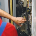 Auf dem Bild sind zwei Elektrotechniker zu sehen, die an einer elektrischen Schalttafel arbeiten.