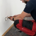 Ein Elektroenergietechniker arbeitet an der Installation einer Steckdose an einer Wand.