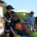 Auf dem Bild beaufsichtigt ein Elementarpädagoge mehrere spielende Kinder im Freien.