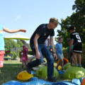 Auf dem Bild beaufsichtigt ein Elementarpädagoge mehrere spielende Kinder im Freien.