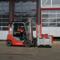 Auf dem Bild ist ein Entsorgungs- und Recyclingtechniker zu sehen, der mithilfe eines Gapelstaplers eine Palette in einem Lagerbereich transportiert.