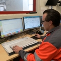 Ein Entsorgungs- und Recyclingtechniker überwacht und steuert Prozesse an mehreren Computermonitoren in einem Kontrollraum.