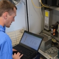 Ein Elektroenergietechniker arbeitet mit einem Laptop an der Wartung eines elektrischen Schaltschranks.