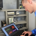 Ein Elektroenergietechniker arbeitet mit einem Laptop an einem Schaltschrank.