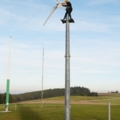 Ein Elektroenergietechniker arbeitet auf einem hohen Mast an einer Windkraftanlage.