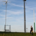 Ein Elektroenergietechniker inspiziert eine Windkraftanlage auf einem Feld.