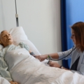 Eine dipl. Gesundheits- und Krankenpflegerin führt eine medizinische Untersuchung an einem Simulationspatienten durch.