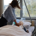 Eine dipl. Gesundheits- und Krankenpflegerin führt an einer Puppe in einem Krankenhausbett eine Wiederbelebungsübung durch.