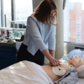 Eine dipl. Gesundheits- und Krankenpflegerin übt Wiederbelebungstechniken an einer medizinischen Puppe.