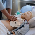 Eine dipl. Gesundheits- und Krankenpflegerin führt an einem medizinischen Simulator Wiederbelebungsmaßnahmen durch.