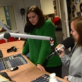 Das Bild zeigt zwei Medienmanagement-Studierende, die in einem Fernsehstudio vor Mikrofonen stehen.