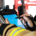 Ein Berufsfeuerwehrmann in Feuerwehrkleidung bedient ein Tablet mit einem Stift.
